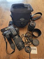 Full kit laid out showing camera body, telephoto lens attached, second lens, caps, hood, USB cable and Optex case