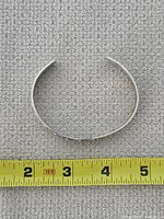 Top view of open cuff against measuring tape showing interior width