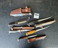 All seven knives laid out with sheaths visible