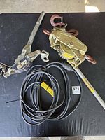 Two come-along winches and one extension cord coiled on table