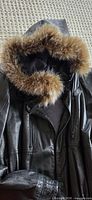 Full view of black leather coat with fur-trimmed hood