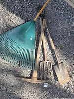 All four yard tools laid on gravel surface