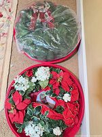 Two red plastic containers, one holding green wreath in plastic