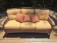 Front view of wicker sofa with cushions and pillows
