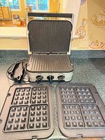 Grill/griddle unit open with grill plates installed, waffle plates, drip tray and scraper visible