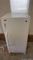 Front view of white GE upright freezer showing handle, lock and control panel