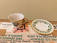 Teacup and saucer front view displaying holly wreath design and gold trim