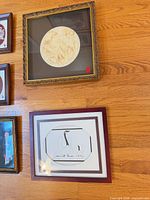 Two framed pieces: square gilt frame with circular bas-relief and maroon frame with crane print