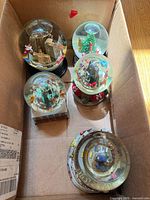 Top view of five snow globes inside box