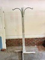 Full view of weathered wood coat rack with cross base and hooks