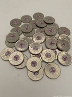 Pile of 33 commemorative quarters showing reverse pink ribbon design