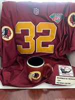 Front view of burgundy #32 jersey draped with mug in foreground