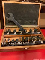 Open case showing router bits arranged in two rails and the included wrench