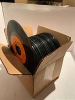 Open box filled with stacked 45 RPM records, no sleeves visible