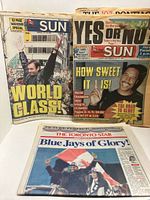 Three newspapers displayed: two Toronto Sun fronts and one Toronto Star front
