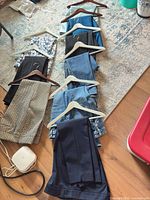 All nine pairs of pants laid out on hangers showing variety of colors and styles