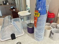 Overview showing bread box, clear canister, purple tumbler, disposable cups, shaker bottle, mugs
