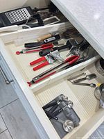 Drawer overview with multiple red KitchenAid utensils and stainless tools visible
