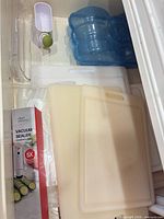 Overall lot showing boxed vacuum sealer, stack of cutting boards, blue ice pack, small dispenser