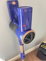 Main vacuum body mounted, showing purple housing, rose-gold accents and dustbin