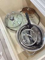 Drawer view showing pot rim, steamer insert, mesh strainer, two glass lids