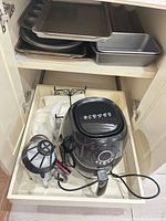 Cabinet view showing air fryer, French press and stacked bakeware