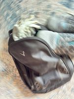 Black carry bag partially open showing white glove and shoes