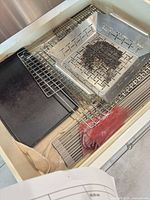 Drawer view showing grill basket, cooling racks, cookie sheet, silicone mat, accessory bag