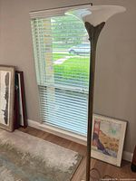 Full view of brass torchiere floor lamp beside window