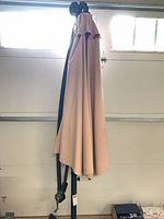Folded beige canopy on black cantilever pole with crank