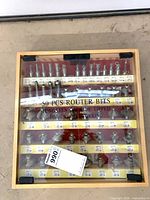 Closed wood case with clear lid showing 50 router bits