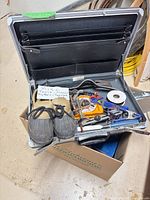 Toolbox in cardboard box containing assorted tools and pair of boots