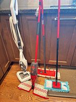 Group of four mops and multiple pads on kitchen floor