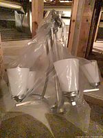 Five-light brushed nickel chandelier wrapped in plastic showing frosted shades and arms