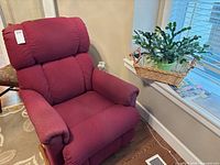Front angled view of burgundy rocker recliner beside area rug edge