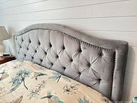 Front view of grey upholstered tufted king headboard with mattress