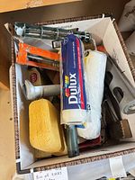 Open Bankers Box displaying Dulux roller cover, roller frame, sponge, paint tray and brushes