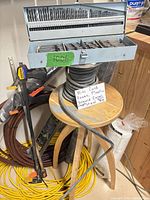 Overview showing drill bit set on stool, clamps, cords, hoses, fabric rolls