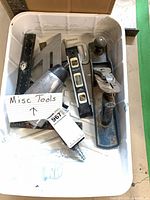 Overview of white bin showing bench plane, spirit level, combination square, speed square, pneumatic tool body