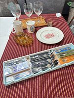 All items arranged on table showing spoons set box, glasses, mugs, plate, tray, amber dish, shot glass