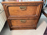 Front view of oak nightstand showing two drawers and brass pulls