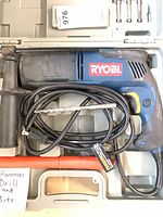 Drill with coiled cord, handle, depth rod in carry case
