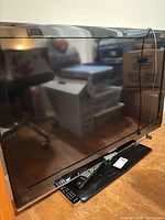 Front view of Samsung TV on stand with remote visible