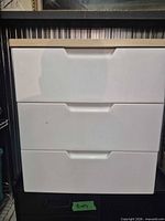 Front view of cabinet showing three drawers and recessed handles