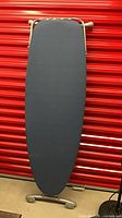 Front view of ironing board standing upright, navy cover visible
