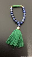 Full view of beaded lapis bracelet with green stone accent and tassel