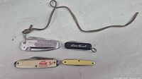 Overview of the four folding pocket knives showing handles, logos and lanyard