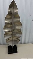 Front view of silver metal leaf sculpture on black stone base