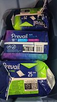 Three packs Prevail Air Daily Briefs showing counts and size labels, visible tear on packaging