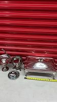 Group view of all four silver plated serveware pieces with measuring tape for scale